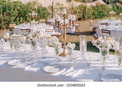 Elegant white decor for a wedding dinner at Villa Italy. The tables are decorated with white flowers in round vases. Tables without people