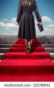 Elegant Woman In Black Coat Climbing A Red Carpet Stairway