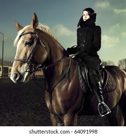 Elegant Woman In A Black Coat Riding On A Brown Horse