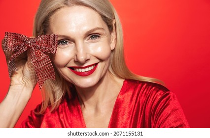 Elegant Woman With Clear Healthy Facial Skin, Red Lips, Holding Christmas Present Ribbon Near Face, Surprise Gift On Winter Holidays, Concept Of New Year And Celebration