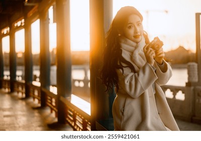 Elegant Woman Holding Vintage Camera in Golden Hour Light at Scenic Outdoor Location, Capturing the Beauty of Sunset. - Powered by Shutterstock