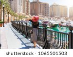 Elegant woman looks at the Marina Walkway in Porto Arabia at the Pearl in Doha, Qatar