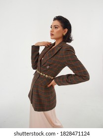 Elegant Woman In Peach Color Silk Slip Dress And Brown Squared Wool Blazer Posing Against Grey Background In Studio. Fashion Look. Caucasian Brunette Female Model With Wet Hair