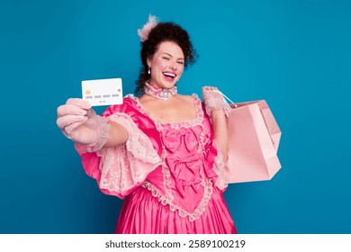 Elegant woman in pink baroque dress holding shopping bag and card against blue background