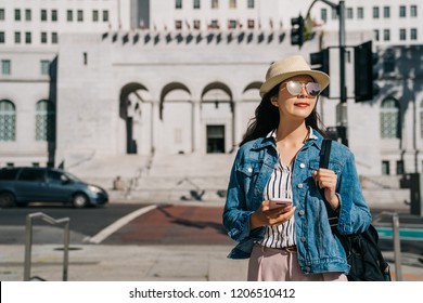 elegant woman relaxing walking on the street and looking at the beautiful sky. office lady using online map app standing in front of the city hall. Relaxing girl lifestyle in sunny city center. - Powered by Shutterstock