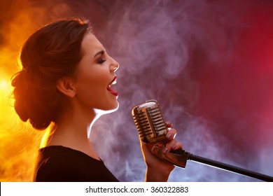Elegant woman singing in colourful smoke, close up