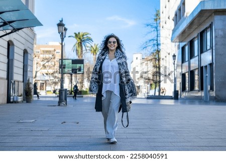 Elegant Woman Smiling.
Portrait Of A Woman Walking Down The Street. She Is In A Positive Attitude And Looking At The Camera.