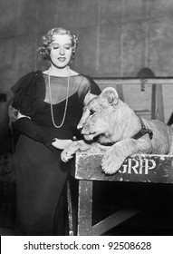 Elegant woman standing next to a lion