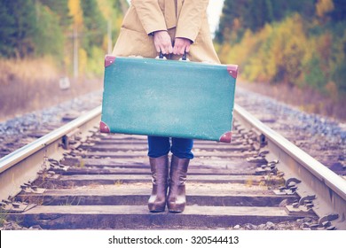 An elegant woman with a suitcase traveling by rail autumn day.