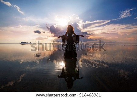Elegant woman walking on water. Sunset and silhouette. 