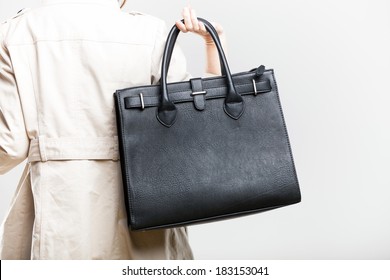 Elegant Woman In White Coat Holding Black Bag, Back View