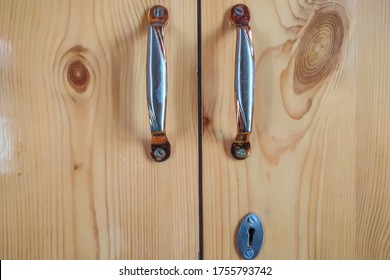 An elegant wooden cupboard with brass designer handles. A key hole in the cupboard.