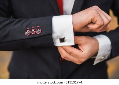 Elegant Young Fashion Man Dressing Up For Wedding Celebration. Color Close Up Image Of Male Hands. Handsome Groom Dressed In Modern Black Formal Suit, White Shirt And Tie Getting Ready For Event.