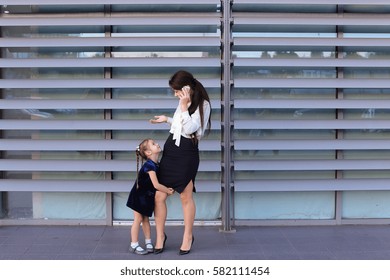 Elegant Young Female Woman, Young Modern Mom, Business Woman Holding Mobile Phone Hand And Talking On Cellphone, Solves Problems, Negotiates Business Meeting With Partners, Spends Time Girl Daughter