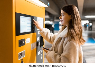 Elegant young girl pays for ticket in parking meter. Woman near terminal in the underground parking
