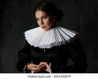 An Elegant Young Lady In An Old Medieval Costume, A Portrait In The Style Of Painting. Spanish Round Collar And Dark Dress, Portrait In The Renaissance Style