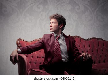 Elegant Young Man Sitting On A Velvet Sofa