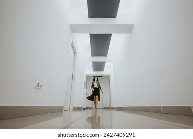 Elegant young woman in business attire walking with confidence down a bright, contemporary office hallway with a minimalist design. - Powered by Shutterstock