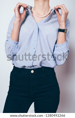 Frau mit Jeansjacke, blauer Bluse und silberner Armbanduhr.