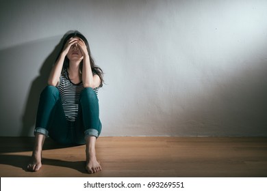 elegant young woman having depression bipolar disorder trouble feeling confusion sitting on wooden floor resting in white background.