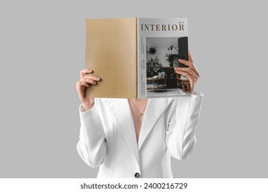 Elegant young woman reading interior magazine on light background - Powered by Shutterstock