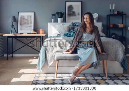Elegant young woman sitting in bedroom. Home interior