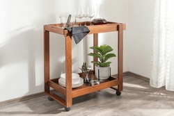 An Elegantly Crafted Wooden Serving Trolley Featuring A Variety Of Stemmed Glasses And A Potted Plant