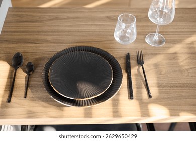 An elegantly designed black dining setup featuring exquisite glassware and fine cutlery