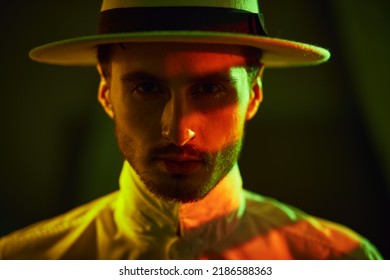 An Elegantly Dressed Brunet Man In White Hat And Shirt Standing In A Dark Room. Mafia And The Criminal World.