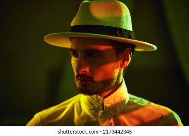 Elegantly Dressed Masculine Man  Stands In A Room With Dim Lighting Looking Thoughtfully Away. Detective Story, Mafia.