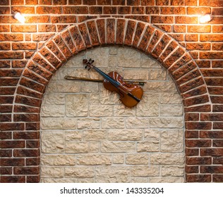Element of the interior stone arch with a violin on a wall