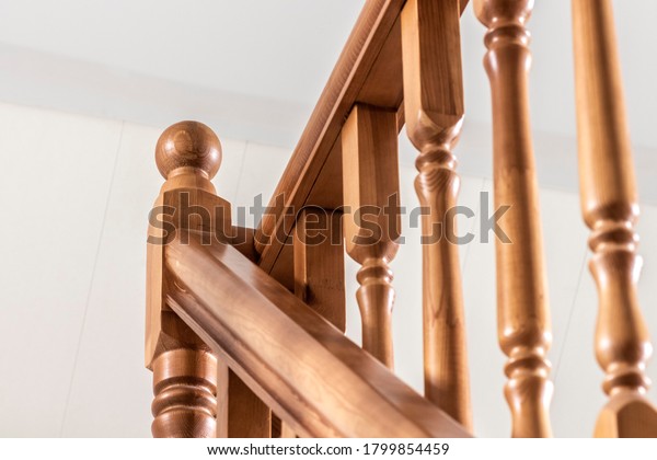Element of a wooden interior staircase. Wooden\
baluster close-up.