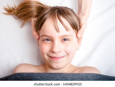 Elementary Age Girl's Head Being Manipulated By Osteopathic Or Chiropractic Manual Therapist In A Pediatric Clinic