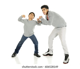 A elementary boy ready to take a punch at his tall big brother.  On a white background. - Shutterstock ID 606528149