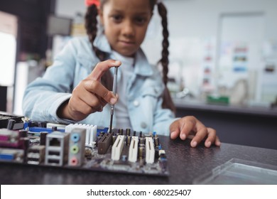 Elementary girl assembling circuit board on desk at electronics lab - Powered by Shutterstock