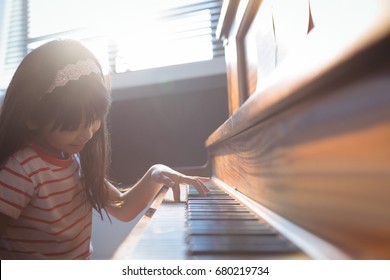 Elementary Girl Practicing Piano In Class At Music School