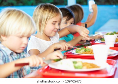 Elementary Pupils Enjoying Healthy Lunch In Cafeteria