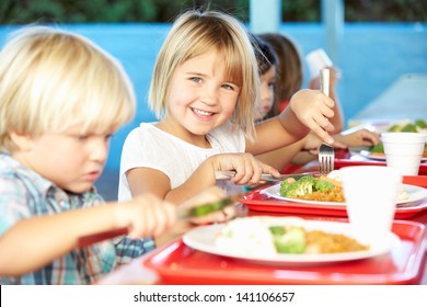 Elementary Pupils Enjoying Healthy Lunch In Cafeteria