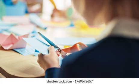 Elementary School Arts & Crafts Class: Over Shoulder Of A Girl Has Fun  On The Handicraft Project, Cuts Paper Figures With Scissors. Creative Young Girl