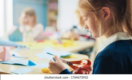 Elementary School Arts & Crafts Class: Over Shoulder Of A Girl Has Fun  On The Handicraft Project, Cuts Paper Figures With Scissors. Creative Young Girl