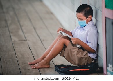 Elementary school Asian male students wearing a medical mask To prevent the coronavirus (COVID 19) in rural schools A student sitting alone reading a book