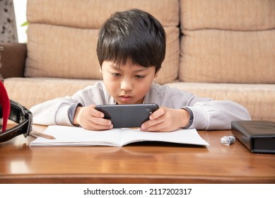 Elementary school boy looking at a smartphone while studying