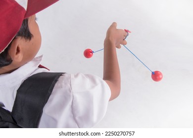 Elementary school boy playing toy "lato lato" Indonesian traditional game, plain white isolated - Shutterstock ID 2250270757