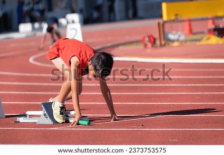 Elementary school boy running in relay at track and field meet