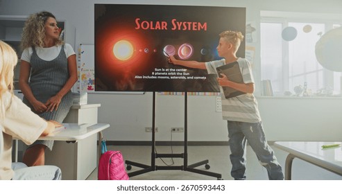 Elementary School Boy with Tablet Computer Giving Presentation About Solar System and Planets in Front of Classmates and Teacher Using Digital Screen. Smart Kids Studying Space Astronomy in Classroom.