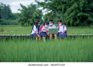 Elementary School Children Asians Living In Rural Areas Wear A Face Mask To Prevent The Coronavirus (COVID 19) In A Rural School In Thailand. Students Are Studying Online With Friends.