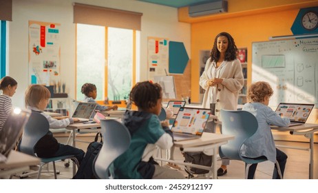 Elementary School Children Learning Basic Computer Skills: Teacher Educating Smart Diverse Kids in a Modern Colorful Classroom. Schoolchildren Getting Experience with Internet and Technology - Powered by Shutterstock