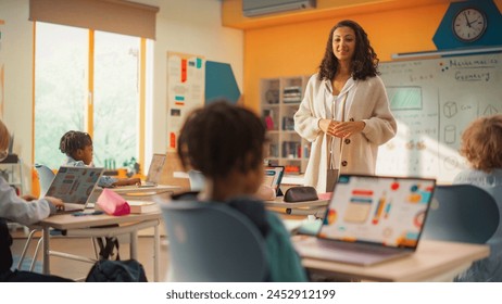 Elementary School Children Learning Basic Computer Skills: Teacher Educating Smart Diverse Kids in a Modern Colorful Classroom. Schoolchildren Getting Experience with Internet and Technology - Powered by Shutterstock