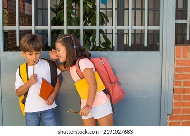 Elementary School Children Smiling With School Bags On Their First Day Of School. Girl And Boy Waiting At The School Gate To Enter. Classmates