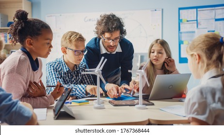 Elementary School Classroom: Enthusiastic Teacher Holding Tablet Computer Explains to a Brilliant Young Children How Wind Turbines Work. Kids Learning about Eco-Friendly Forms of Renewable Energy - Shutterstock ID 1767368444